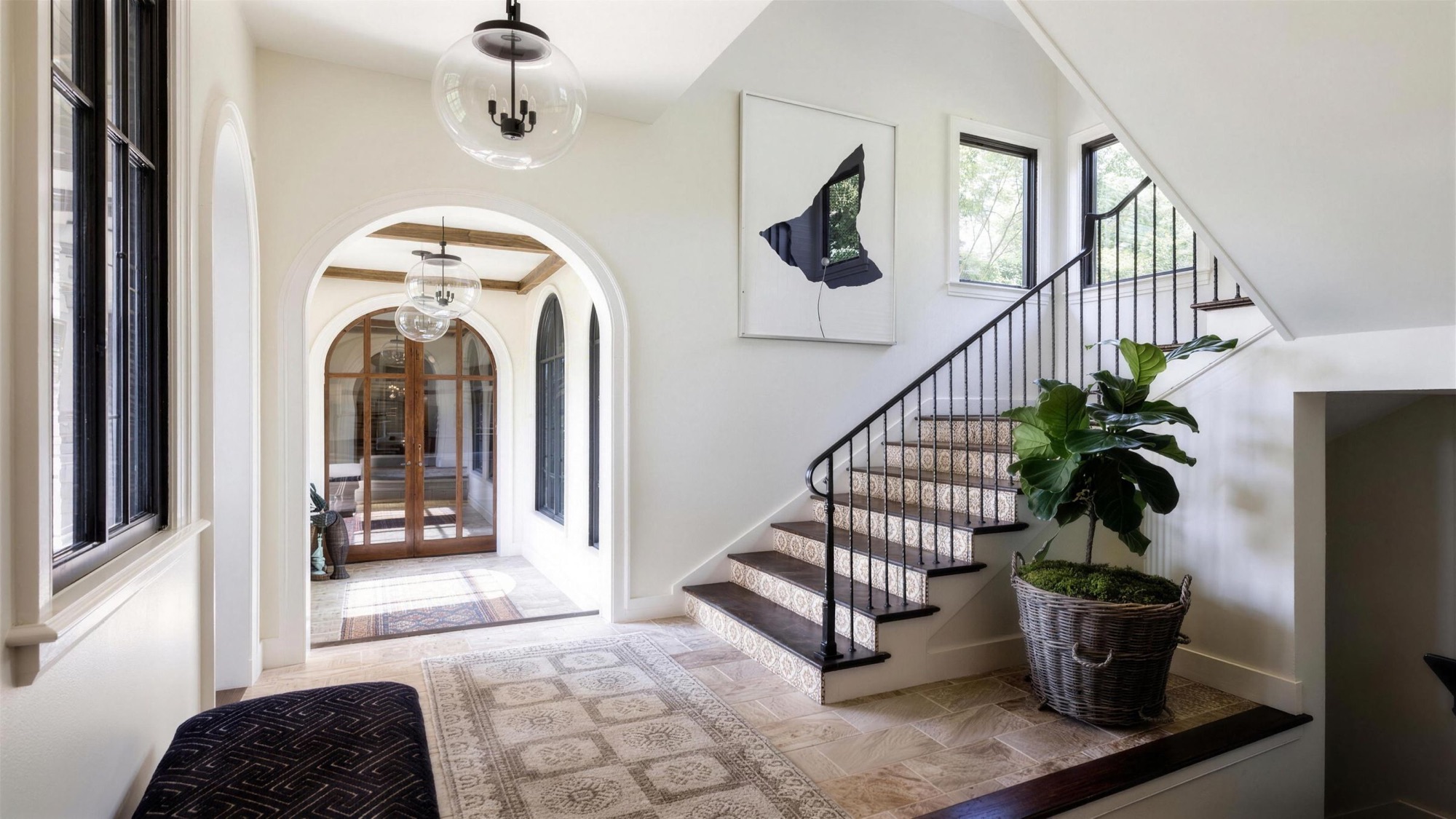 A patterned runner in a bright hallway with an arched doorway and a staircase