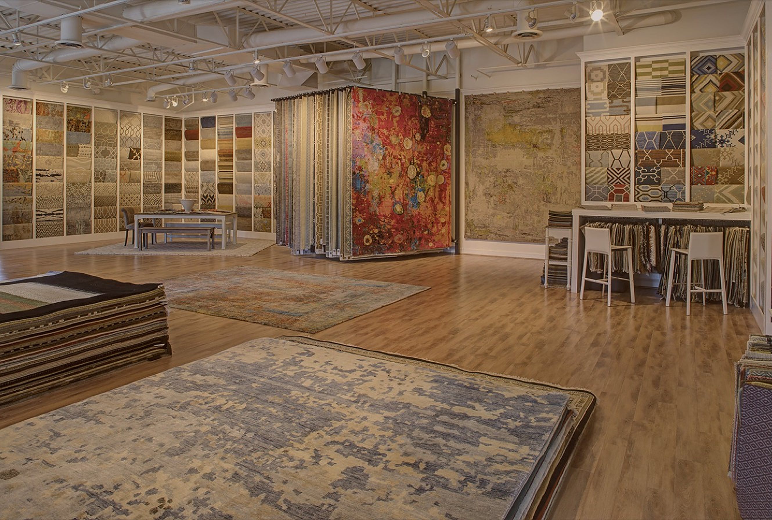 The Senneh Knot showroom floor, with rugs laid out, a rack of hanging rugs and walls of samples